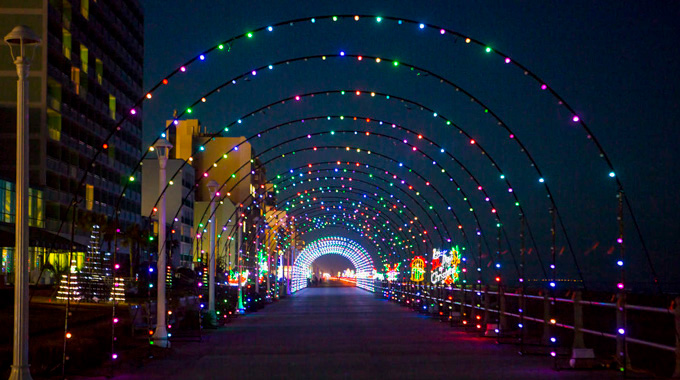 A drive-through archway illuminated by holiday lights