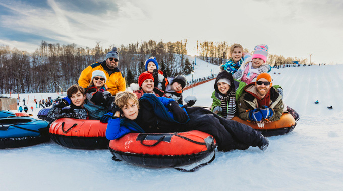 Group posing for a photo atop their tubes at Winterplace Ski Resort's tubing park
