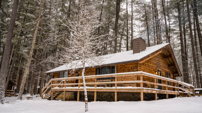 Snow covers the roof and wraparound porch of a North Bend State Park cabin