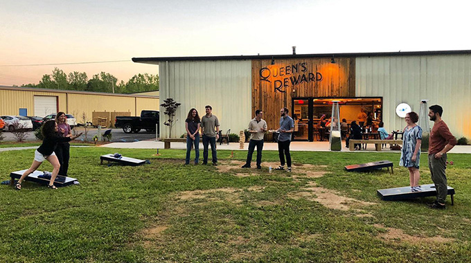 An outdoor green space with cornhole games draws visitors outside Queen’s Reward Meadery in Tupelo, Mississippi. | Photo courtesy Queen’s Reward Meadery