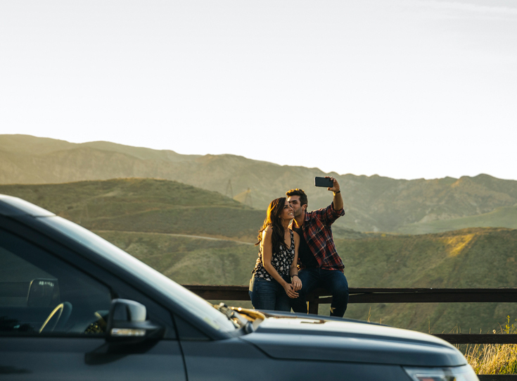 Man kissing woman's cheek while taking selfie at the roadside Man kissing woman's cheek while taking selfie at the roadside