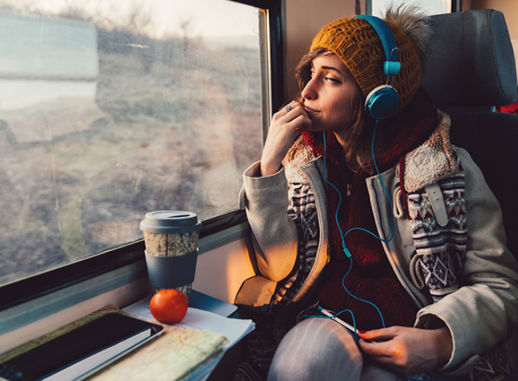 Woman traveling on train listing to podcast Woman traveling on train listing to podcast