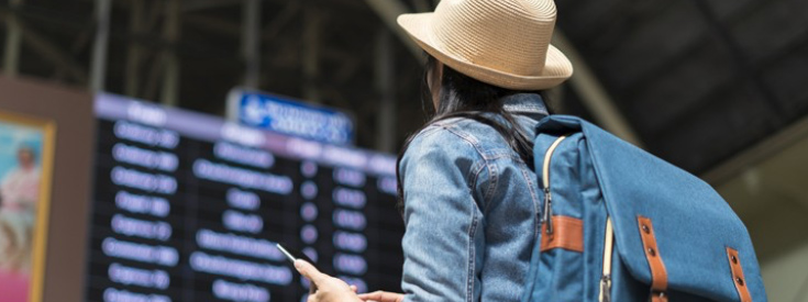 Woman looking at arrivals board at airport Woman looking at arrivals board at airport