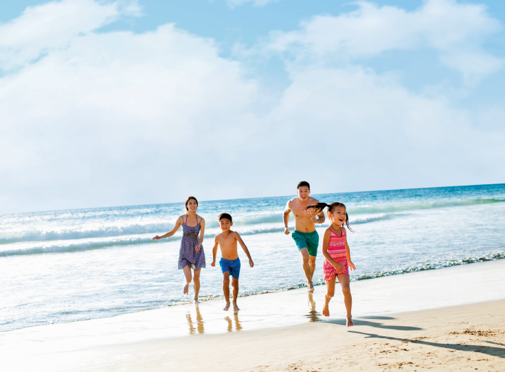 Family of 4 running along a sandy beach Family of 4 running along a sandy beach