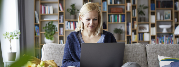 Woman sitting on a sofa looking at a laptop