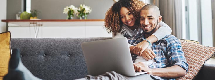 Couple using laptop on couch Couple using laptop on couch