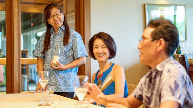 Islander Sake Brewery owner Chiaki Takahashi serving sake samples to a couple.