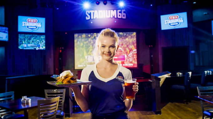 Stadium 66 waitress serving chicken wings and a glass of beer.