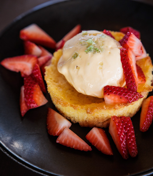 Butter cake topped with strawberry slices and a scoop of vanilla ice cream