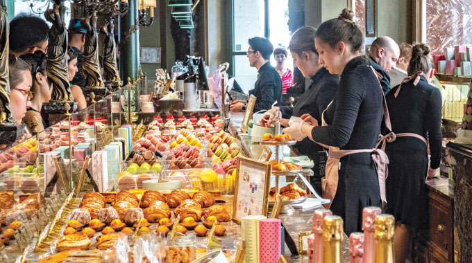 Laduree employees pack sweets from the pastry shop's display case.