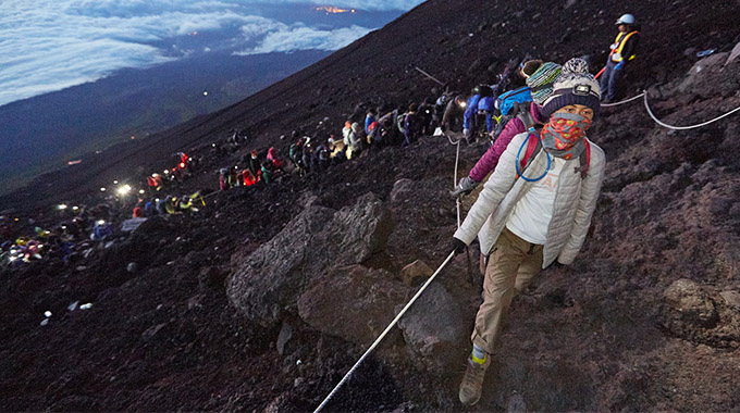A line of hikers wearing headlights climbs in the pre-dawn darkness on Mount Fuji. | Photo by Rob Andrew