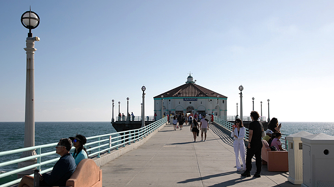 People walking along the Manhattan Beach Pier toward Roundhouse Aquarium