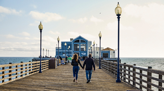 Couple walking hand in hand down Oceanside Pier