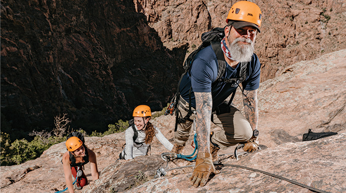 Via ferrata climbers ascending a canyon wall.