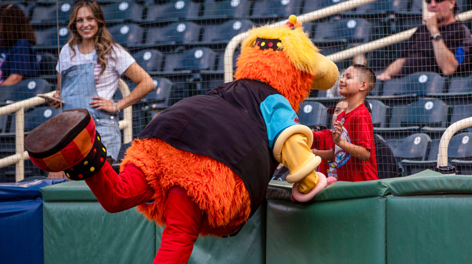 Orbit, the Isotopes mascot, greets a young boy during a game.