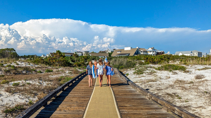 Watersound Club guests walking along a boardwalk from the beach.